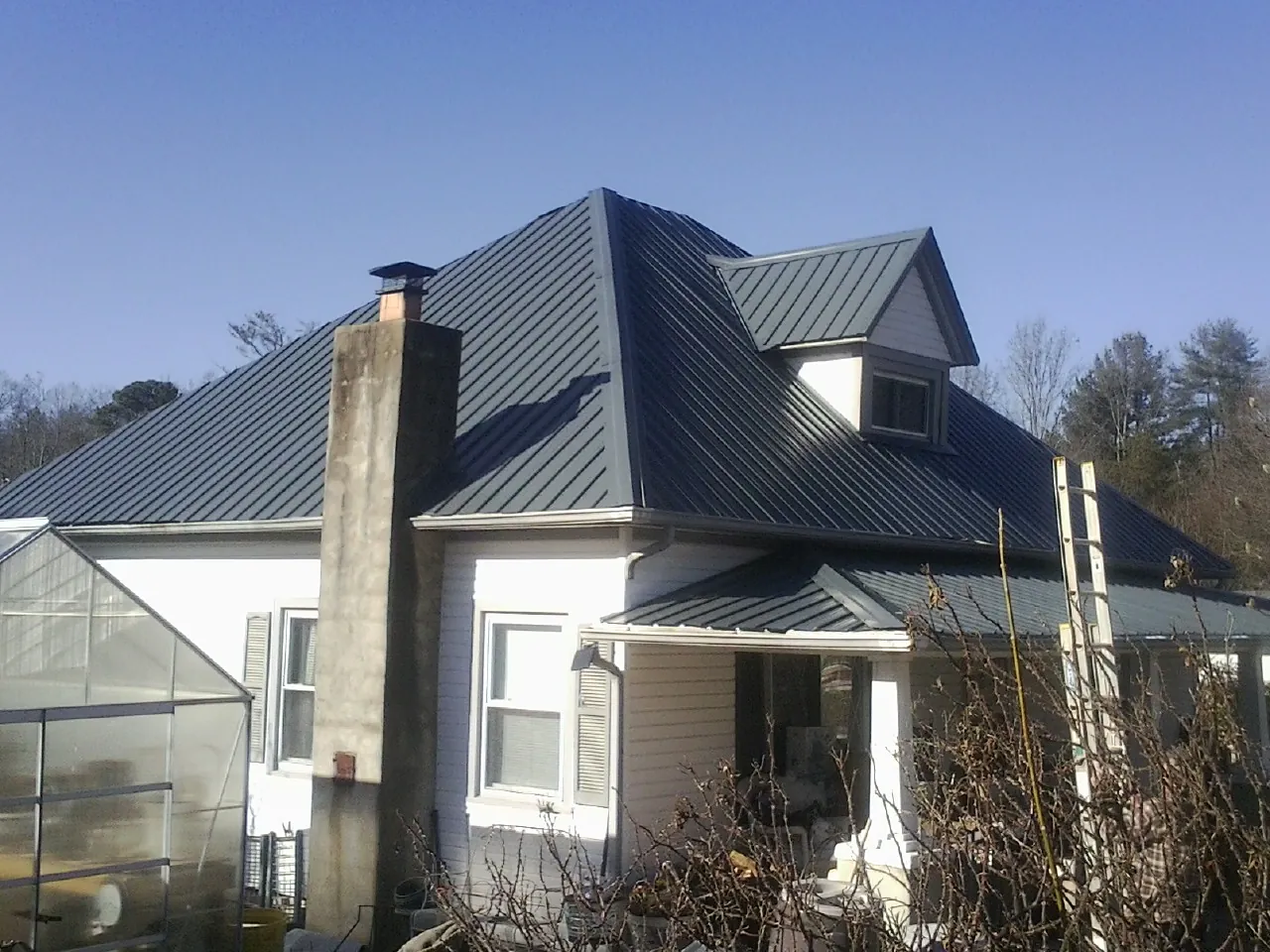 Dark blue standing seam metal roof on a white farmhouse with dormer — Slate & Tile Roof Repair by Roofing Brothers in Hermiston