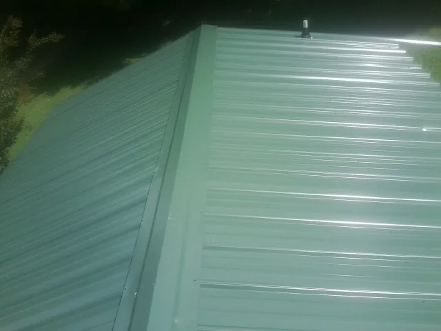New green metal panels meeting at the ridge of a roof — Flat Roof Repair work by our crew in Hermiston