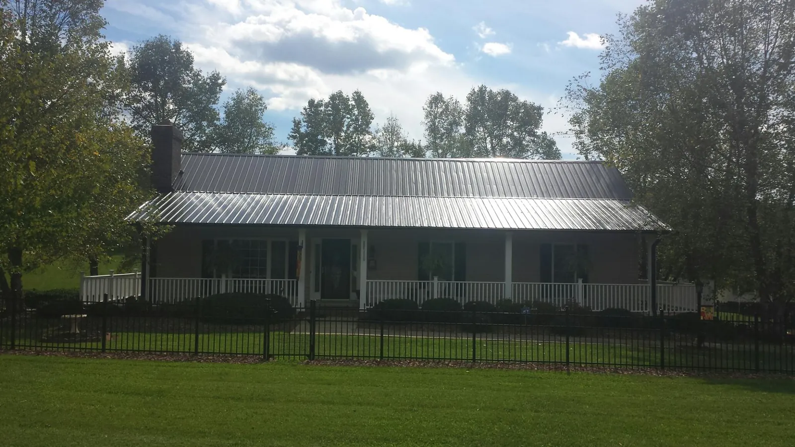 Gray metal roof on a brick ranch with a full width front porch — Gutter Guard Installation work by our crew in Hermiston