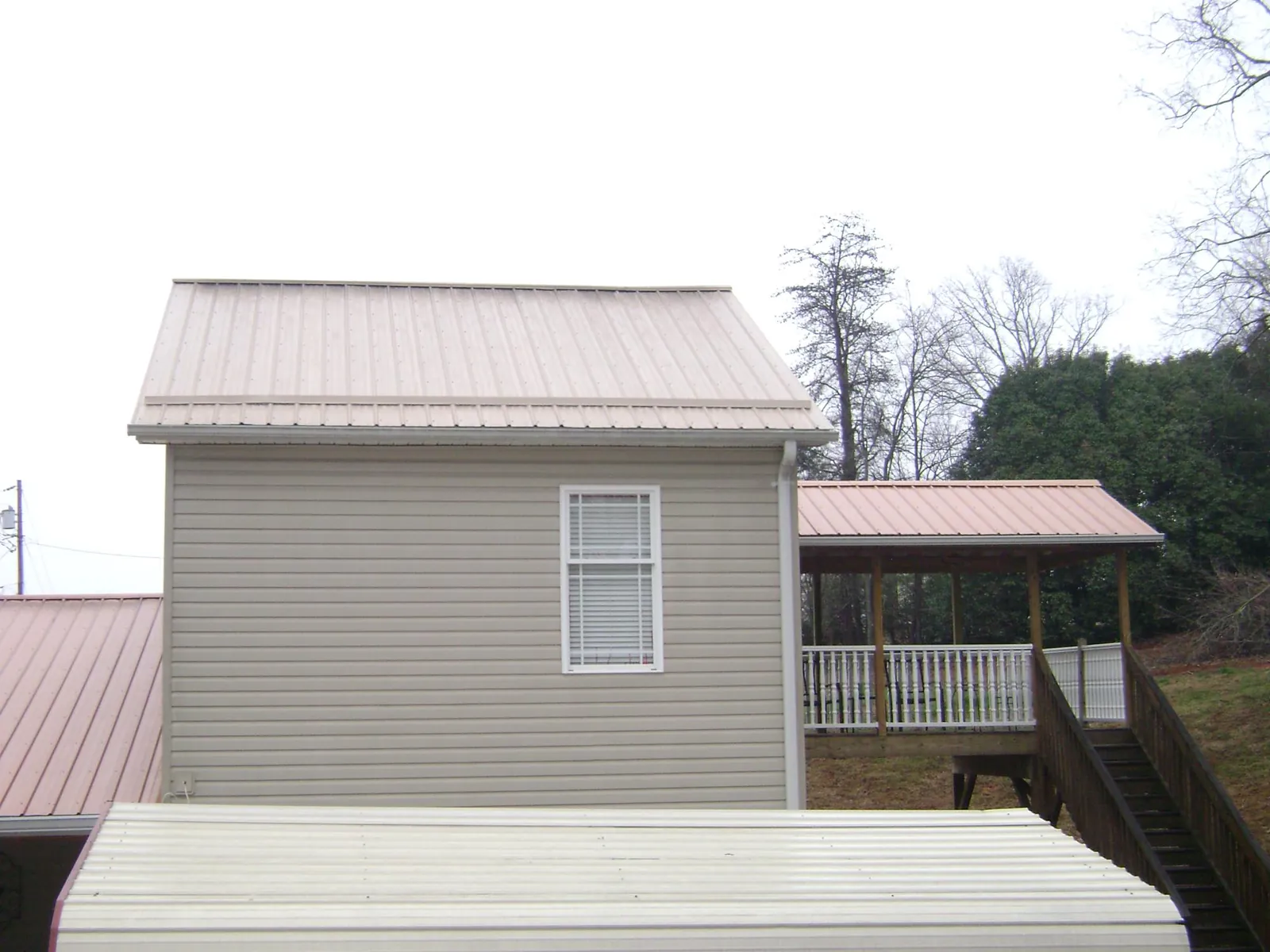 Tan metal roofs on a two story addition and attached porch, from a Roof Replacement job in Hermiston