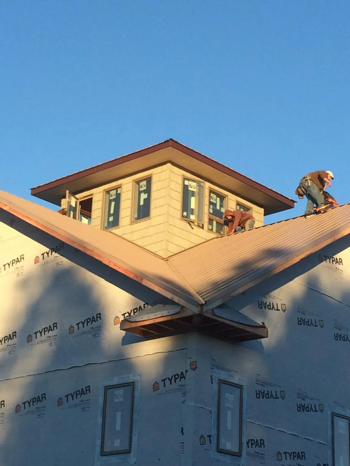 Roofers working around a rooftop cupola on a new metal roof at sunset — Roof Waterproofing in Hermiston by Roofing Brothers